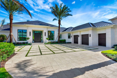 Large beach style one-story stucco house exterior photo in Miami with a metal roof and a brown roof