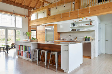 Mid-sized trendy single-wall light wood floor open concept kitchen photo with an undermount sink, flat-panel cabinets, white cabinets, gray backsplash, stone slab backsplash, stainless steel appliances, an island and gray countertops