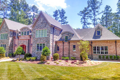 This is an example of a large eclectic two-storey brick house exterior in Charlotte with a mixed roof.