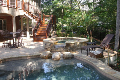 Design ideas for a mid-sized traditional backyard custom-shaped pool in Atlanta with a hot tub and natural stone pavers.