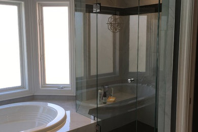 Example of a large trendy master gray tile and porcelain tile porcelain tile and gray floor bathroom design in Toronto with raised-panel cabinets, white cabinets, a two-piece toilet, gray walls, an undermount sink, quartz countertops and a hinged shower door