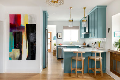 Eat-in kitchen - small coastal u-shaped eat-in kitchen idea in Minneapolis with a single-bowl sink, shaker cabinets, turquoise cabinets, solid surface countertops, subway tile backsplash, stainless steel appliances, a peninsula and white countertops