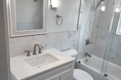 Mid-sized minimalist kids' gray tile and ceramic tile vinyl floor, gray floor and single-sink bathroom photo in New York with shaker cabinets, white cabinets, a two-piece toilet, gray walls, an undermount sink, quartz countertops, white countertops, a niche and a freestanding vanity