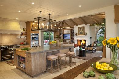 Eat-in kitchen - mid-sized mediterranean l-shaped limestone floor and beige floor eat-in kitchen idea in San Francisco with an island, beaded inset cabinets, distressed cabinets, soapstone countertops, beige backsplash, ceramic backsplash and black appliances