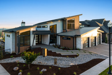 Inspiration for a large modern white two-story stone house exterior remodel in Portland with a metal roof and a black roof