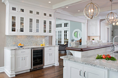 Eat-in kitchen - l-shaped medium tone wood floor eat-in kitchen idea in New York with an undermount sink, shaker cabinets, white cabinets, wood countertops, white backsplash, subway tile backsplash, stainless steel appliances and an island