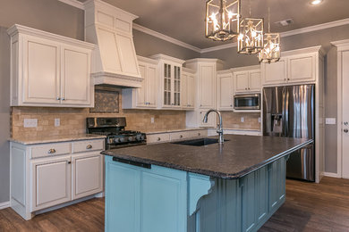 Mid-sized elegant l-shaped porcelain tile eat-in kitchen photo in Dallas with an undermount sink, brown backsplash, stainless steel appliances, an island, raised-panel cabinets, white cabinets, granite countertops and ceramic backsplash