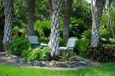 This is an example of a mid-sized tropical backyard full sun garden for summer in Miami with natural stone pavers.
