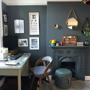 Photo of a mid-sized transitional study room in London with grey walls, dark hardwood floors, a standard fireplace, a metal fireplace surround, a freestanding desk and brown floor.