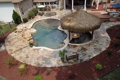 Example of a large island style backyard custom-shaped pool fountain design in Other