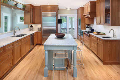 Photo of a large modern galley eat-in kitchen in Boston with a double-bowl sink, shaker cabinets, medium wood cabinets, quartz benchtops, white splashback, subway tile splashback, stainless steel appliances, medium hardwood floors and with island.
