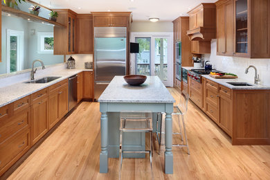 Large minimalist galley medium tone wood floor eat-in kitchen photo in Boston with a double-bowl sink, shaker cabinets, medium tone wood cabinets, quartz countertops, white backsplash, subway tile backsplash, stainless steel appliances and an island