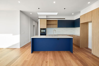 Kitchen - mid-sized modern light wood floor kitchen idea in Melbourne with a drop-in sink, white backsplash, an island and white countertops