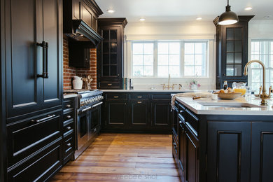 Inspiration for a large transitional l-shaped eat-in kitchen in New York with beaded inset cabinets, black cabinets, white splashback, stainless steel appliances, with island, an undermount sink, stone slab splashback, light hardwood floors and marble benchtops.