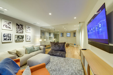 Mid-sized trendy enclosed light wood floor and brown floor family room photo in DC Metro with beige walls, no fireplace and a wall-mounted tv