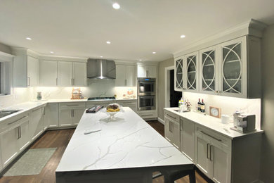 Klassische Küche mit Glasfronten, weißen Schränken, Küchenrückwand in Weiß, Küchengeräten aus Edelstahl, dunklem Holzboden, Kücheninsel und braunem Boden in New York