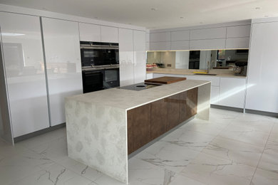 Photo of a contemporary open plan kitchen in Other with quartz worktops, mirror splashback and an island.