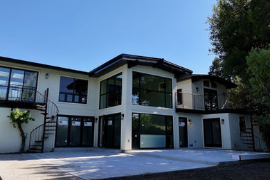 Large white two-story glass house exterior photo in San Francisco with a hip roof, a metal roof and a black roof