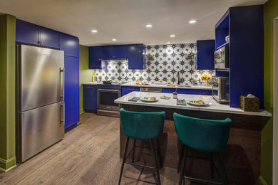 Example of a small transitional galley dark wood floor and brown floor enclosed kitchen design in New York with an undermount sink, recessed-panel cabinets, blue cabinets, quartz countertops, multicolored backsplash, porcelain backsplash, stainless steel appliances, a peninsula and multicolored countertops