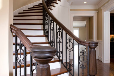 Inspiration for a large traditional wood curved staircase in Houston with painted wood risers and metal railing.