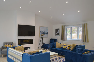 Large contemporary living room in Cornwall with white walls, a wall mounted tv and brown floors.
