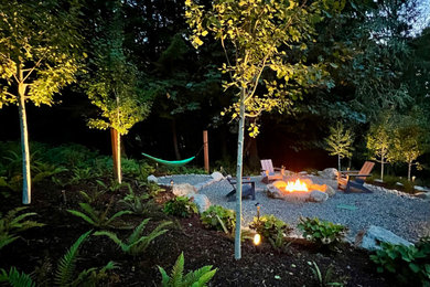 This is an example of a rustic partial sun backyard gravel landscaping in Seattle with a fire pit.