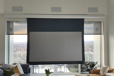 Modelo de cine en casa abierto contemporáneo grande con paredes beige, moqueta, pantalla de proyección y suelo beige