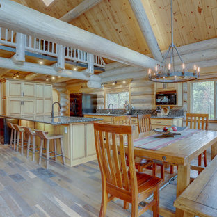 Cette photo montre une grande salle à manger ouverte sur le salon montagne avec un mur marron, un sol marron et sol en stratifié.