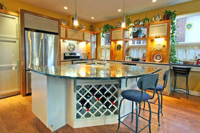 Open concept kitchen - mid-sized traditional l-shaped medium tone wood floor and brown floor open concept kitchen idea in Denver with an undermount sink, shaker cabinets, beige cabinets, white backsplash, subway tile backsplash, stainless steel appliances and an island