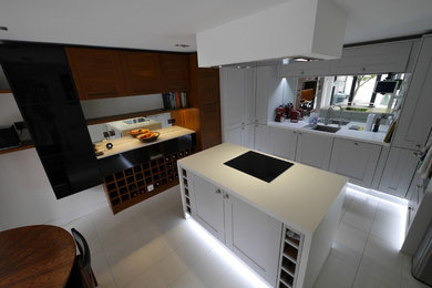 ロンドンにある低価格の中くらいなコンテンポラリースタイルのおしゃれなキッチン (アンダーカウンターシンク、シェーカースタイル扉のキャビネット、中間色木目調キャビネット、珪岩カウンター、メタリックのキッチンパネル、ミラータイルのキッチンパネル、シルバーの調理設備、セラミックタイルの床、白い床、白いキッチンカウンター) の写真