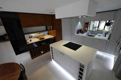 Inspiration for a medium sized contemporary u-shaped kitchen/diner in London with a submerged sink, shaker cabinets, medium wood cabinets, quartz worktops, metallic splashback, mirror splashback, stainless steel appliances, ceramic flooring, an island, white floors and white worktops.