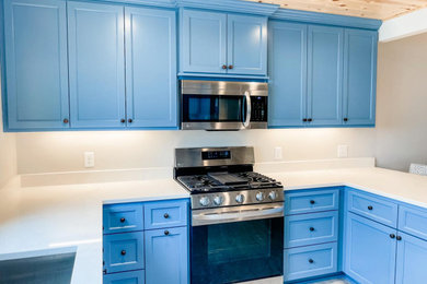 Inspiration for a mid-sized coastal laminate floor, gray floor and wood ceiling eat-in kitchen remodel in Minneapolis with an undermount sink, shaker cabinets, blue cabinets, quartz countertops, stainless steel appliances, an island and white countertops