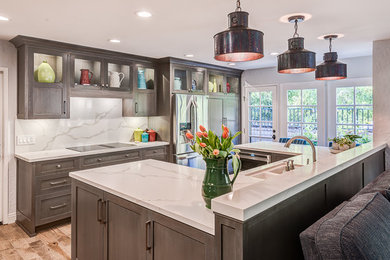 Mid-sized arts and crafts u-shaped eat-in kitchen in Los Angeles with an undermount sink, recessed-panel cabinets, grey cabinets, quartz benchtops, white splashback, stone slab splashback, stainless steel appliances, light hardwood floors, a peninsula and brown floor.