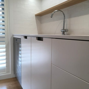 Large contemporary kitchen pantry designs - Large trendy galley medium tone wood floor and multicolored floor kitchen pantry photo in Canberra - Queanbeyan with an undermount sink, white cabinets, granite countertops, white backsplash, ceramic backsplash, stainless steel appliances, an island and beige countertops