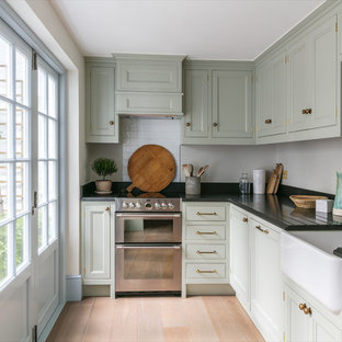 Kleine, Geschlossene Klassische Küche ohne Insel in L-Form mit Landhausspüle, Schrankfronten mit vertiefter Füllung, grünen Schränken, Granit-Arbeitsplatte, Küchenrückwand in Weiß, Rückwand aus Keramikfliesen, beigem Boden, Küchengeräten aus Edelstahl und hellem Holzboden in London