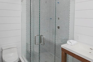 Example of a mid-sized transitional 3/4 black and white tile and ceramic tile porcelain tile and gray floor bathroom design in New York with open cabinets, medium tone wood cabinets, a one-piece toilet, white walls, an integrated sink and solid surface countertops