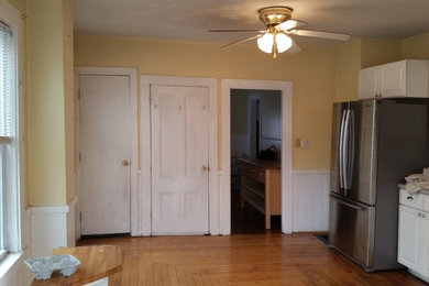 Example of a mid-sized classic l-shaped medium tone wood floor eat-in kitchen design in Boston with a single-bowl sink, raised-panel cabinets, white cabinets, granite countertops, subway tile backsplash, stainless steel appliances and an island