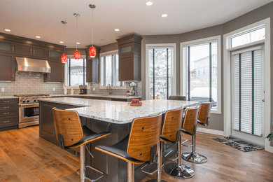Photo of a large contemporary l-shaped eat-in kitchen in Calgary with an undermount sink, shaker cabinets, dark wood cabinets, quartz benchtops, grey splashback, subway tile splashback, stainless steel appliances, medium hardwood floors and with island.
