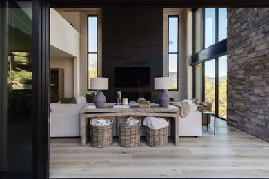 Large transitional open concept light wood floor, vaulted ceiling and brick wall living room photo in Phoenix with white walls, a ribbon fireplace, a metal fireplace and a wall-mounted tv
