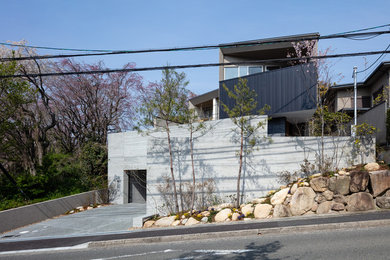 Inspiration for a mid-sized modern split-level concrete grey house exterior in Kobe with a shed roof and a metal roof.