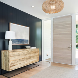 Immagine di un ingresso o corridoio stile marinaro con pareti nere, parquet chiaro, una porta singola, una porta in legno chiaro e pavimento beige