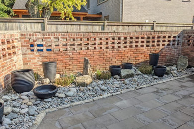 This is an example of a contemporary partial sun concrete paver and stone fence landscaping in Other.