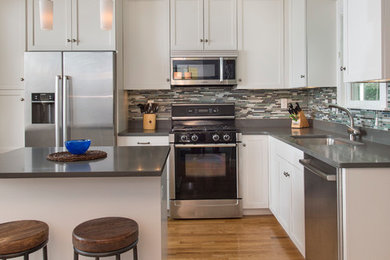 Mid-sized transitional l-shaped medium tone wood floor eat-in kitchen photo in Boston with shaker cabinets, white cabinets, quartz countertops, gray backsplash, glass sheet backsplash, stainless steel appliances, an island and a single-bowl sink