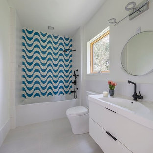 Cette image montre une salle d'eau minimaliste de taille moyenne avec un placard à porte plane, des portes de placard en bois brun, une baignoire en alcôve, un combiné douche/baignoire, un WC à poser, un carrelage bleu, des carreaux de béton, un mur jaune, un sol en carrelage de porcelaine, un lavabo intégré, un plan de toilette en terrazzo et une cabine de douche avec un rideau.