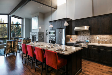 Inspiration for a large rustic galley medium tone wood floor eat-in kitchen remodel in Sacramento with a double-bowl sink, shaker cabinets, dark wood cabinets, solid surface countertops, beige backsplash, ceramic backsplash, stainless steel appliances and an island