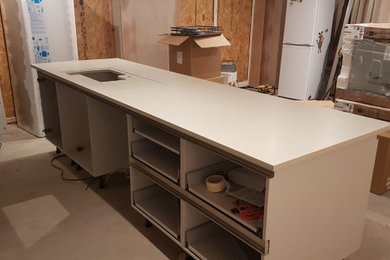 Inspiration for a contemporary kitchen/diner in West Midlands with an integrated sink, flat-panel cabinets, composite countertops, an island and white worktops.