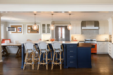 This is an example of a large transitional l-shaped open plan kitchen in New York with a drop-in sink, shaker cabinets, white cabinets, wood benchtops, blue splashback, ceramic splashback, coloured appliances, dark hardwood floors, with island and brown floor.