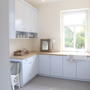 Mid-sized contemporary kitchen pantry ideas - Inspiration for a mid-sized contemporary u-shaped gray floor and cement tile floor kitchen pantry remodel in Bremen with blue cabinets, wood countertops, an integrated sink, flat-panel cabinets, white backsplash, porcelain backsplash, stainless steel appliances and no island