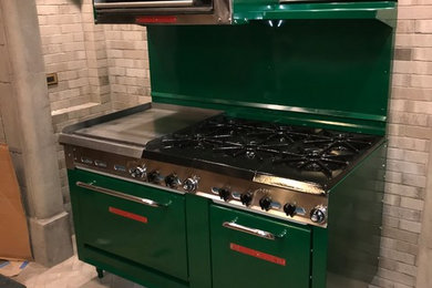Mid-sized mountain style brick floor kitchen photo in Chicago with a farmhouse sink, raised-panel cabinets, colored appliances and an island