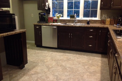Enclosed kitchen - mid-sized modern u-shaped enclosed kitchen idea in Detroit with a double-bowl sink, raised-panel cabinets, dark wood cabinets, laminate countertops, stainless steel appliances and no island